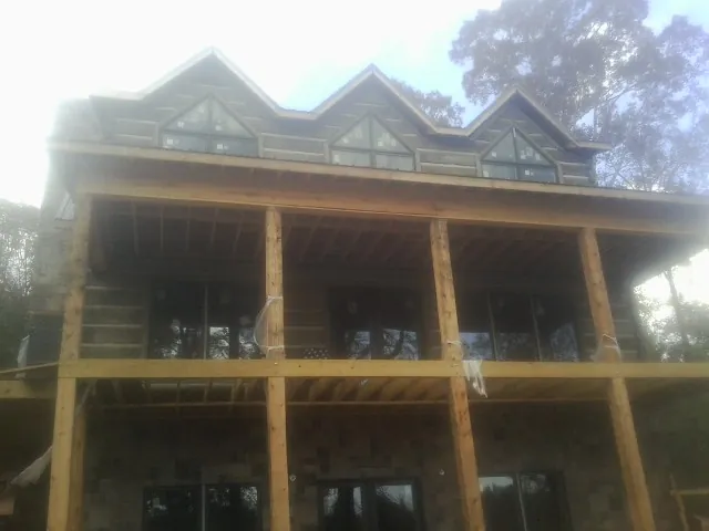 Dormers and porch framing on a large log home under construction — Roof Coating work by our crew in Onaga