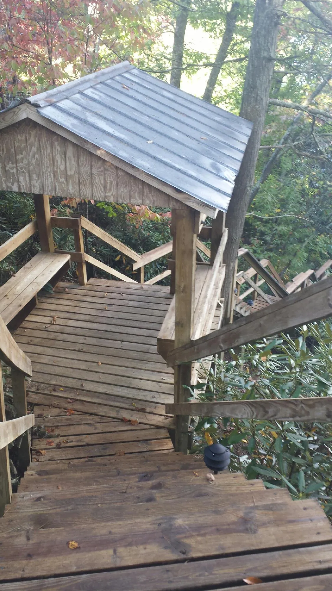 Metal roofed shelter over wooden steps on a wooded walkway — Skylight Repair & Installation work by our crew in Onaga