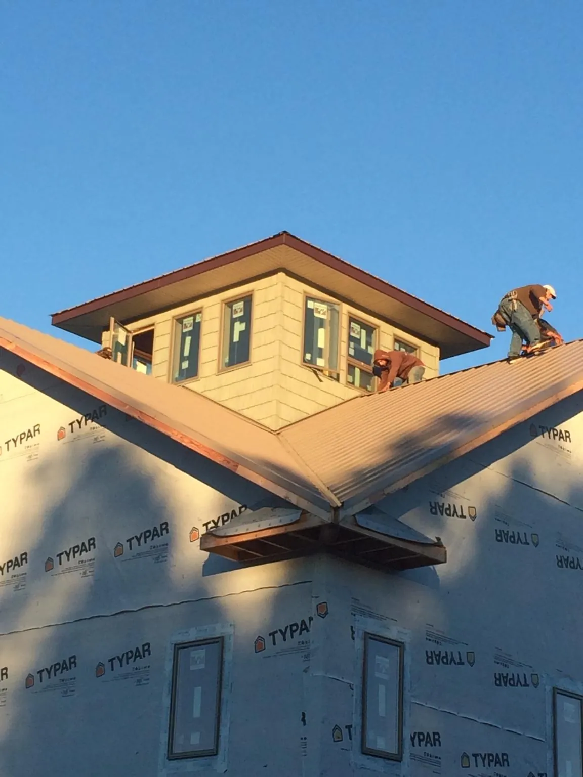 Roofers working around a rooftop cupola on a new metal roof at sunset — Roof Waterproofing in Onaga by Roofing Brothers